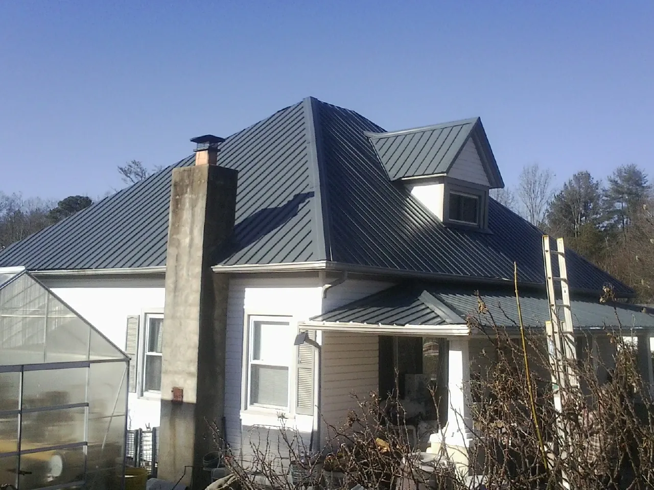 Dark blue standing seam metal roof on a white farmhouse with dormer — Slate & Tile Roof Repair by Roofing Brothers in East Templeton
