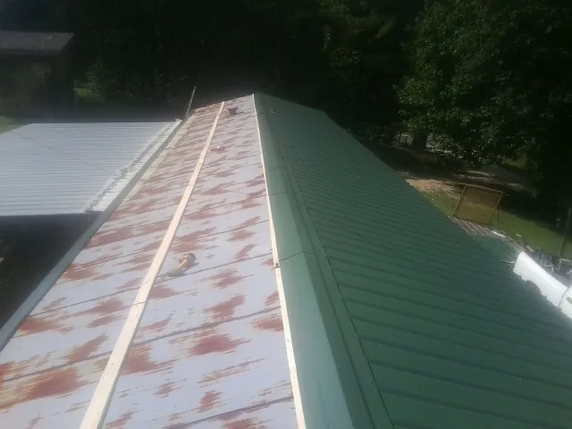 Old rusted panels beside newly installed green metal roofing — Wind Damage Roof Repair by Roofing Brothers in East Templeton