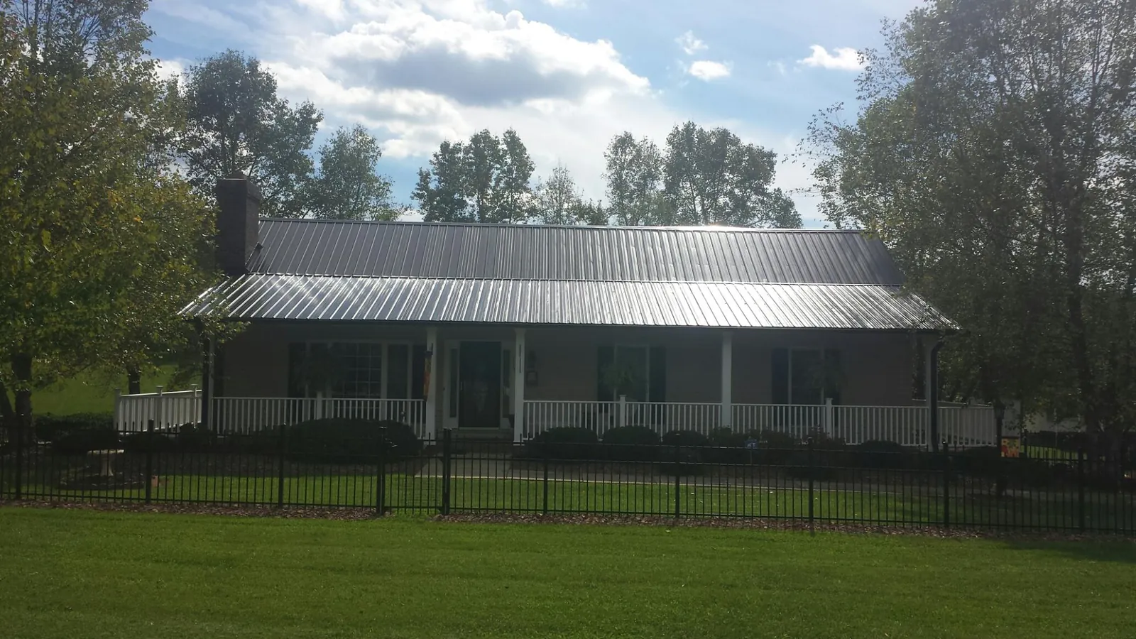Gray metal roof on a brick ranch with a full width front porch — Gutter Guard Installation work by our crew in East Templeton