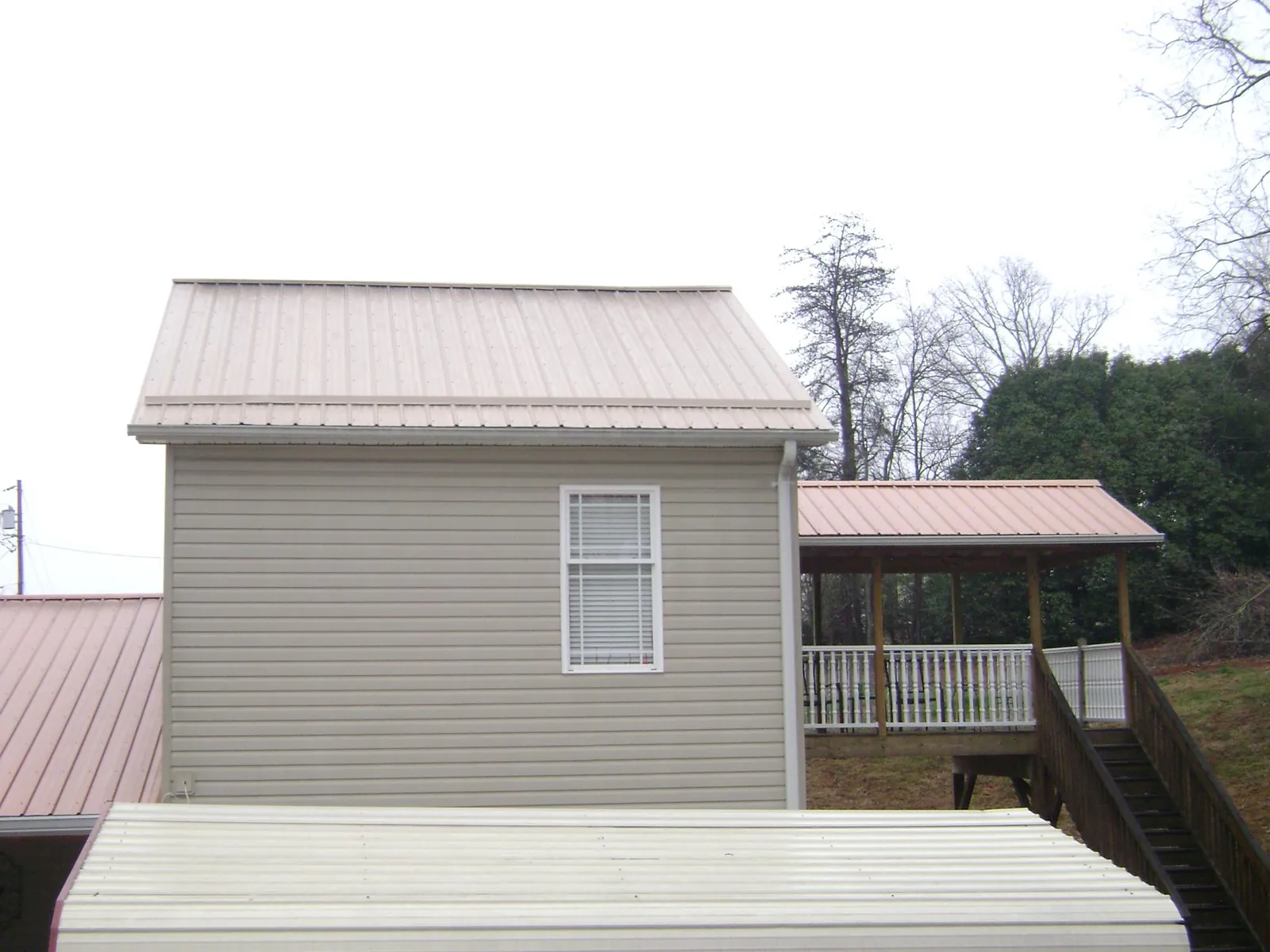 Tan metal roofs on a two story addition and attached porch, from a Roof Replacement job in East Templeton