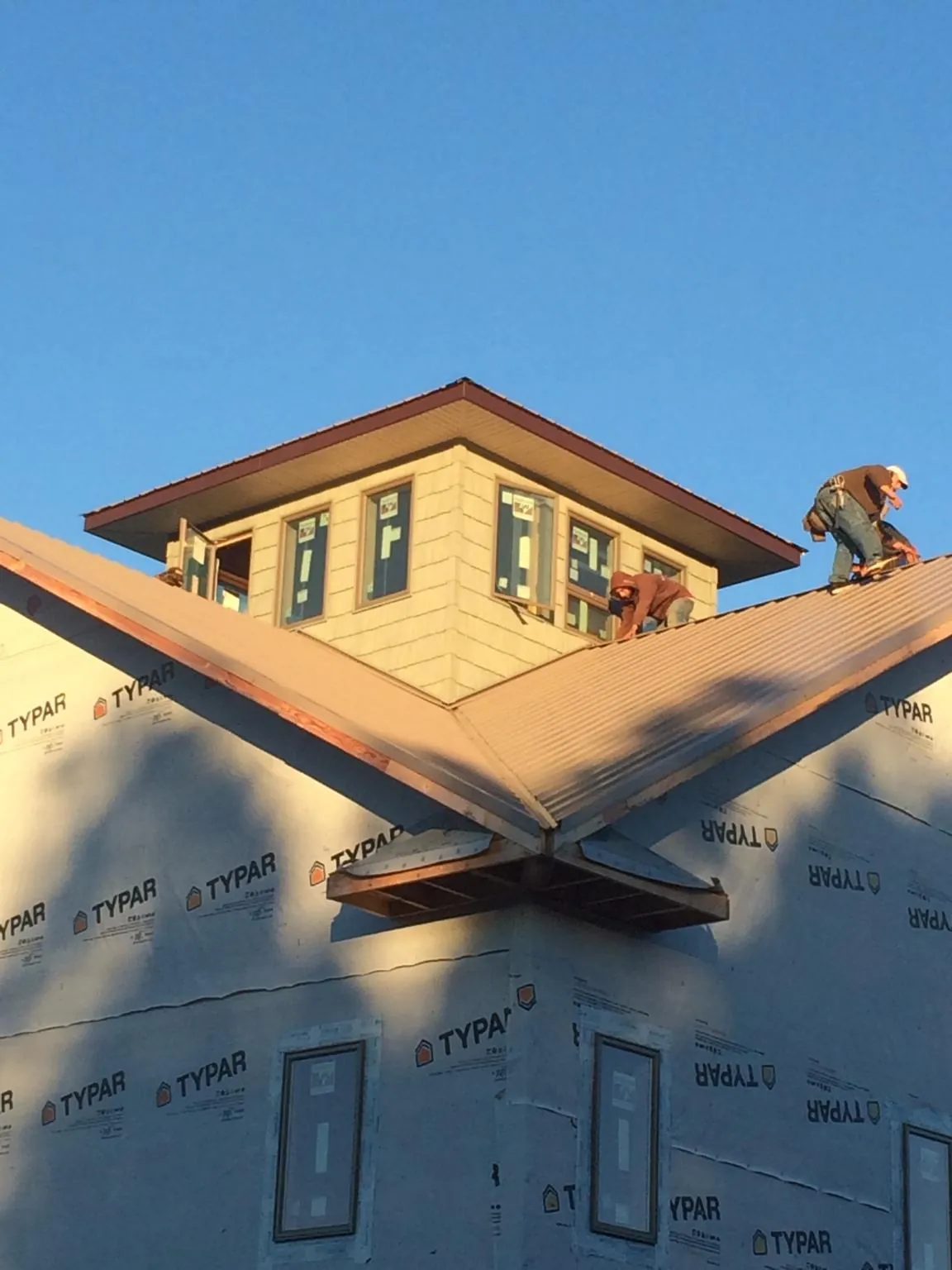 Roofers working around a rooftop cupola on a new metal roof at sunset — Roof Waterproofing in East Templeton by Roofing Brothers